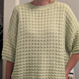 Person wearing a light green textured sweater indoors.