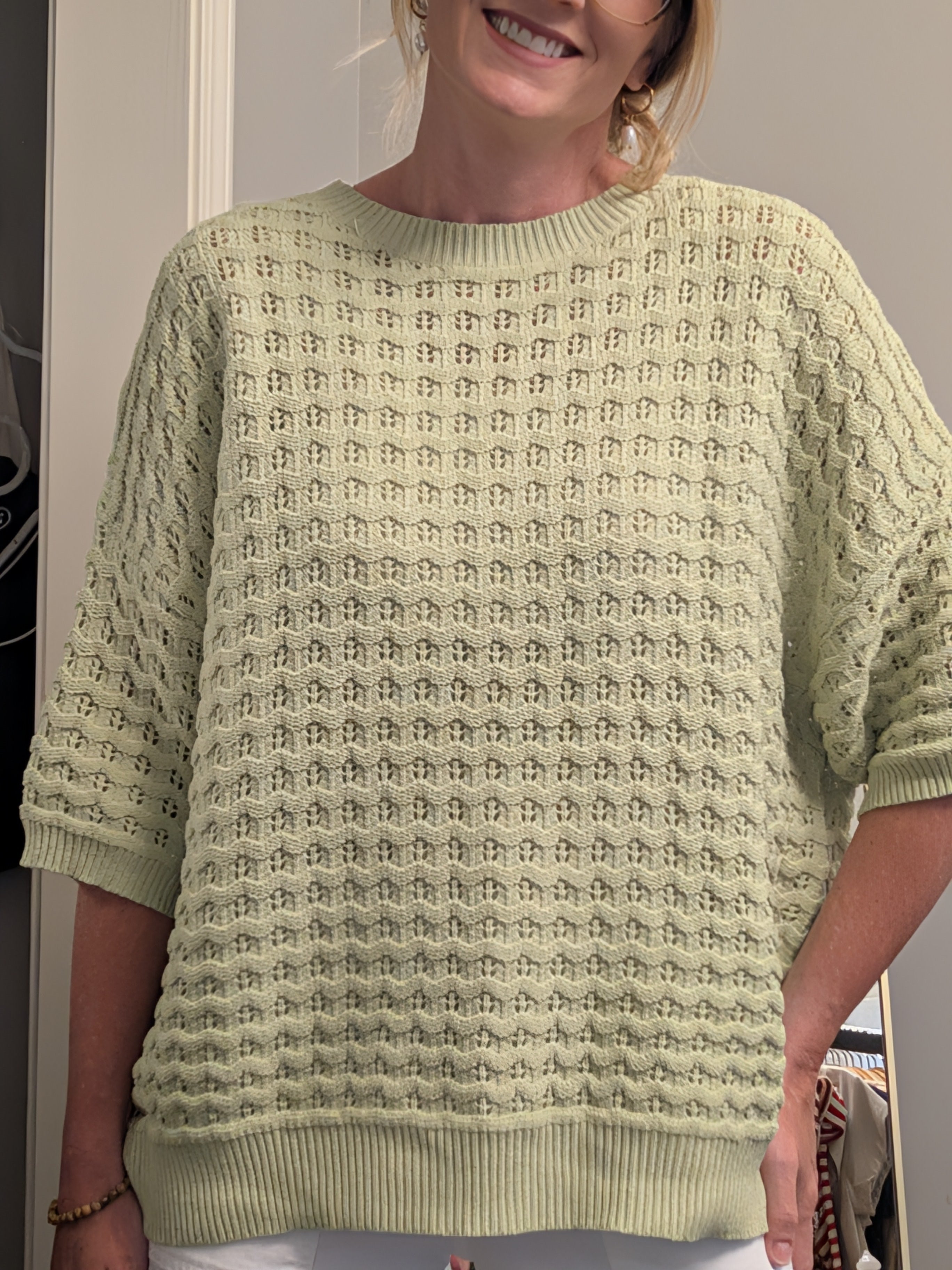 Person wearing a light green textured sweater indoors.